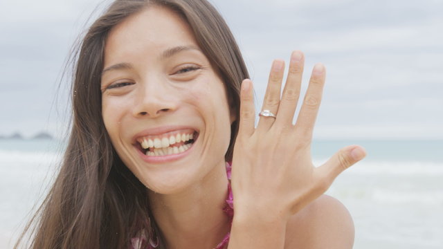 Engagement ring. Woman on beach showing ring after marriage proposal. Excited cute girl in wedding concept on Hawaii wearing flower Lei during holiday travel. Young lovers in love. RED EPIC.