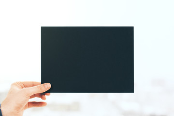 Hand holding black paper sheet