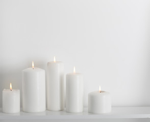 Obraz na płótnie Canvas white candles burning on a white shelf