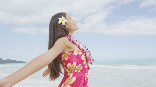 Happy serene woman relaxing on hawaii beach praising freedom smiling on hawaiian beach wearing sarong and lei with arms stretched out. Mixed race female model enjoying sun in meditation zen. RED EPIC.