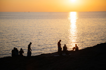 Fototapeta premium People silhouettes on the beach at sunset time