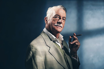 Cigar smoking retro 1940 senior businessman. Studio shot.