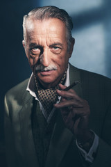 Cigar smoking retro 1940 senior businessman. Studio shot.