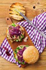 Burger with meat of duck with red onion and lettuce.