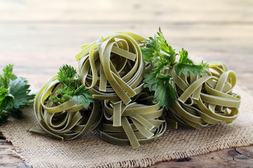 ortica,pasta grezza  con foglie di ortica in tegame di metallo sfondo rustico