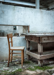 Fototapeta na wymiar Holztisch und Holzstuhl in einer alten Werkstatt. Lost Place.