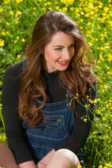 Beautiful young girl among yellow flowers