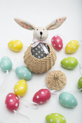 Toy Easter bunny in wicker basket with colorful dyed eggs
