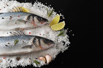 two seabass fish on salt with with lemon, lime, rosemary and spi