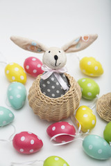 Toy Easter bunny in wicker basket with colorful dyed eggs