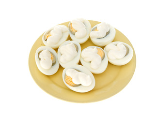 Eggs under mayonnaise on a yellow plate isolated