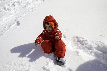 child with red ski suit in the snow