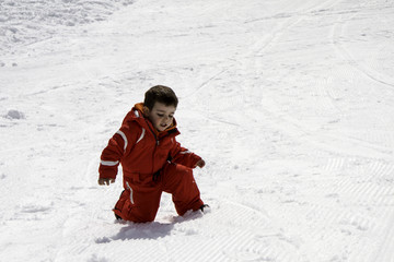 Fototapeta na wymiar child with red ski suit in the snow