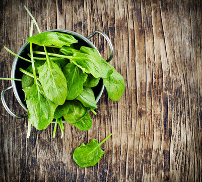 Fresh spinach in bowl on wooden background