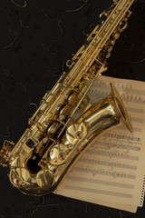 Golden saxophone and music sheets on a black background