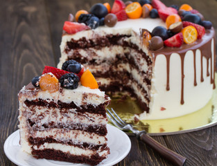 Chocolate cake with various berries and rose on wooden table