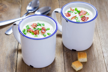 Creamy potato soup garnished with bacon and green onion, served in mug