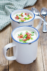 Creamy potato soup garnished with bacon and green onion, served in mug