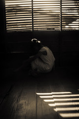 Mysterious girl in white dress sitting in abandon house