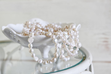 high key image of white pearls necklace on vintage table. selective focus
