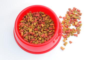 Fototapeta na wymiar Red pet feeder / bowl filled with dry kibble on isolated background