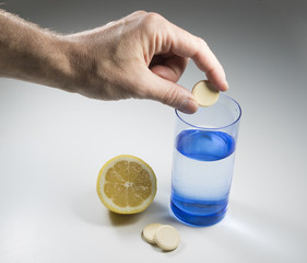 Hand dropping  vitamin C tablet into glass