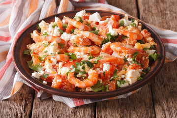 Shrimp with tomatoes and feta cheese on a plate close-up. horizontal
