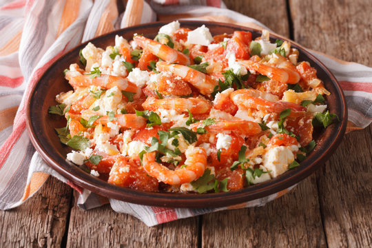 Shrimp with tomatoes and feta cheese on a plate close-up. horizontal
