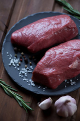 Close-up of fresh uncooked asado beefsteaks on a basalt plate
