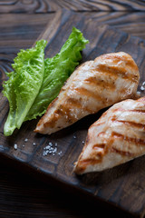 Grilled chicken breast fillets with green salad leaves, close-up
