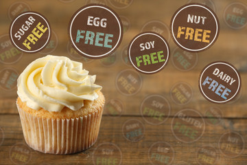 Delicious tasty cupcake and signs with text on wooden background