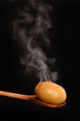 Cuchara de madera con patata hervida en fondo negro.Patata caliente.