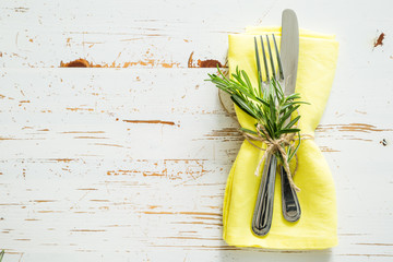 Spring table setting with rosemary and yellow napkin
