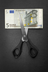 Concept of spending money - scissors cut money on black background
