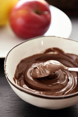 Melted chocolate in bowl, on wooden background