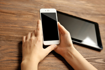 A tablet and female hands using mobile phone, on the wooden background