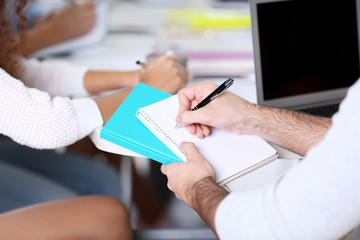 Fototapeta premium Young man sitting and making notes at the office meeting