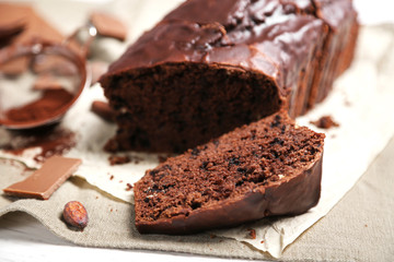 Chocolate sliced cake with icing on tablecloth