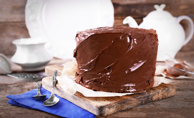 Chocolate cake with two spoons and blue tablecloth on a wooden boards background