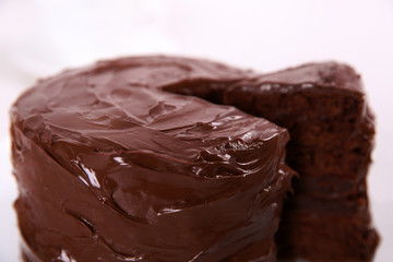 Chocolate cake on plate with a cut piece on unfocused background, closeup