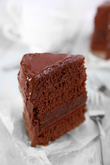 A piece of chocolate cake with forks on wooden table background, closeup