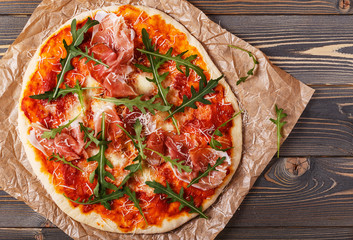 Homemade pizza with prosciutto and arugula.