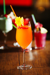 Glasses of cocktails on bar background