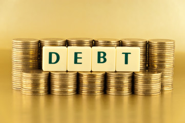 the letters DEBT with stacks of coins