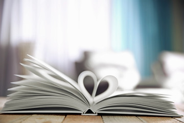 Sheets of book curved into heart shape on unfocused background