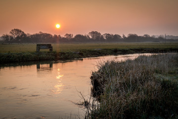 stone seat on river bank at sunrise