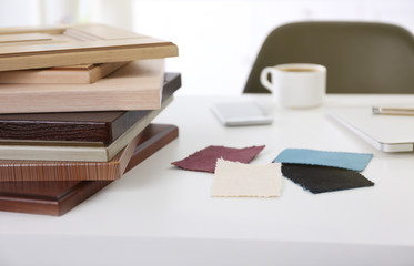 Samples of wooden panels, pieces of cloth for furniture and door on white table