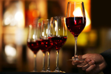 Male hand holding glasses of wine in the bar