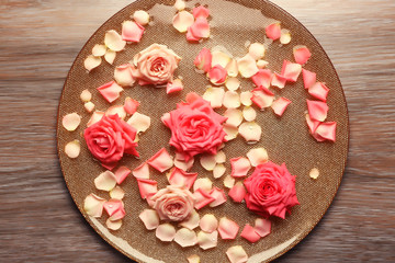 Pink rose petals in golden bowl with water on wooden background
