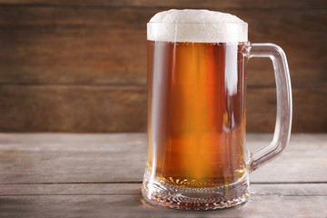 Glass mug of light beer on wooden table, close up